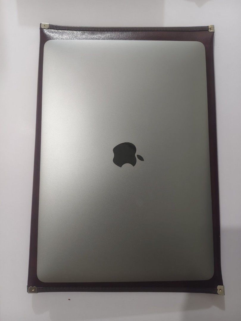 Apple Macbook Pro Open for swap (Category: Laptops & Notebooks) located in Manila. Submitted by abbyoo2025 (Listing ID 1397852612, Image 2). Description: Apple Macbook Pro 2018 1tb. Features a silver finish and a keyboard with a trackpad. The screen displays a login screen. Includes a brown leather case. with charger only .