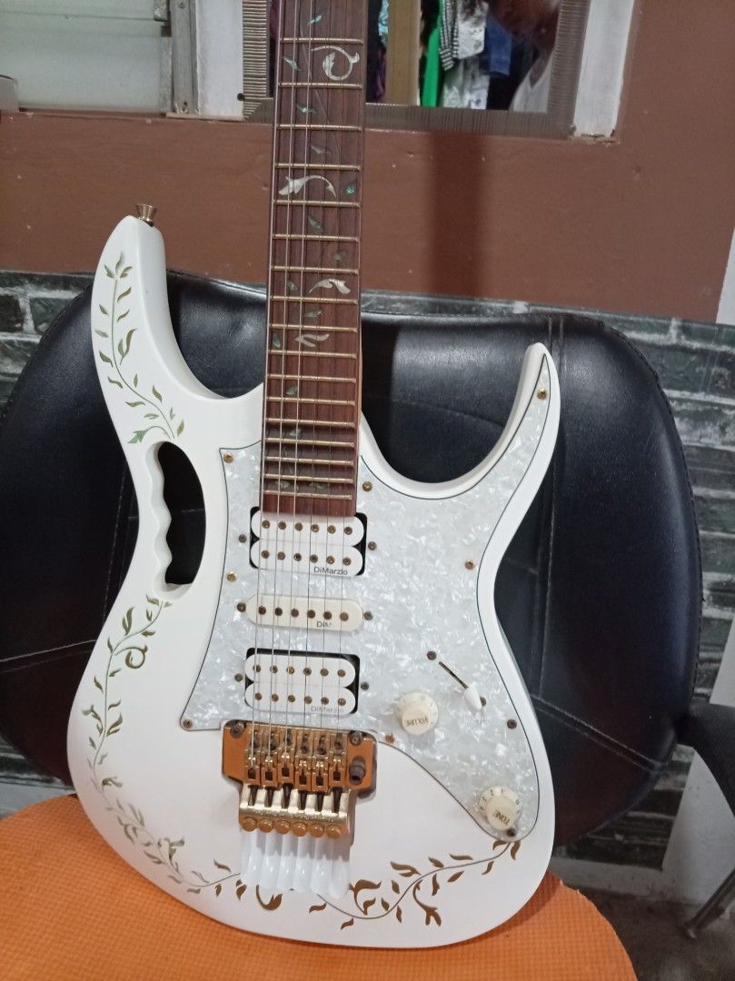 Ibanez Jem Electric Guitar (Category: Musical Instruments) located in Agdangan. Submitted by hairulmusicalcolection (Listing ID 1397856044, Image 1). Description: White Ibanez Jem electric guitar. Features a pearlescent pickguard and floral inlay on the fretboard. The body has a floral design. Includes gold hardware and a tremolo system. The headstock has the Ibanez logo. The guitar has two knobs and three pickups..
