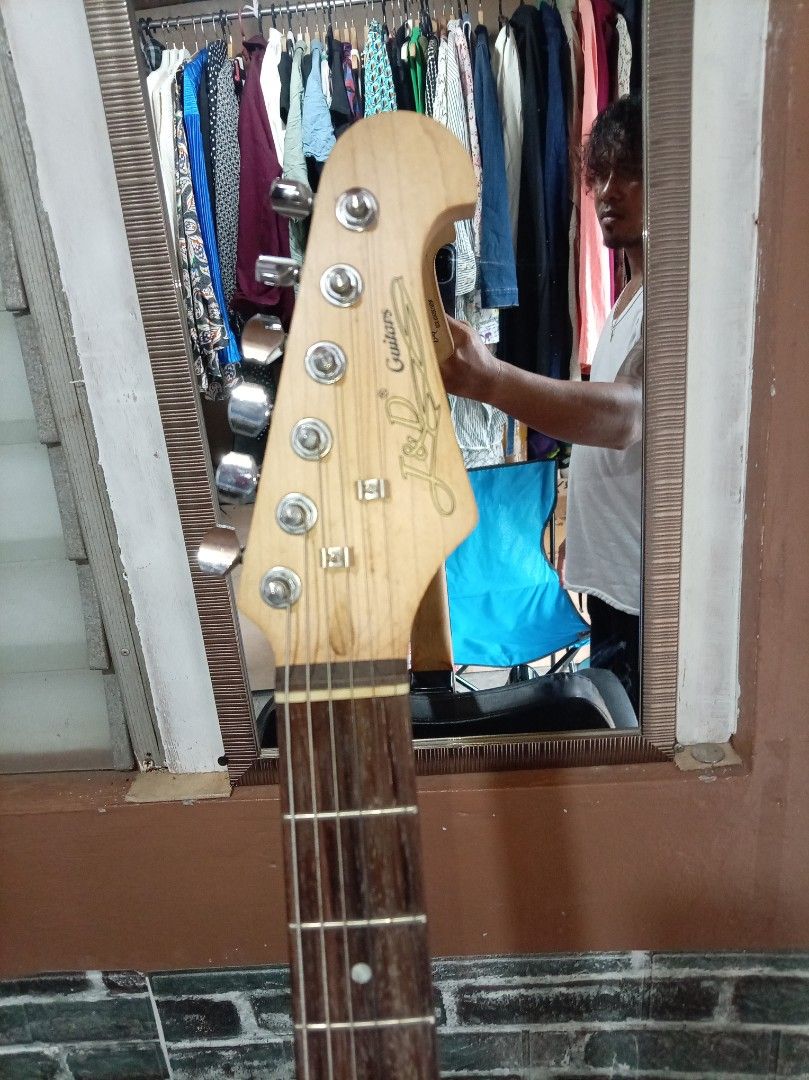 J&D Fender Electric Guitar (Category: Musical Instruments) located in Agdangan. Submitted by hairulmusicalcolection (Listing ID 1397828387, Image 3). Description: - Black J&D Fender electric guitar - White pickguard - Three single-coil pickups - Tremolo bridge - Maple neck - J&D Guitars logo on headstock - Six tuning pegs - Black body.