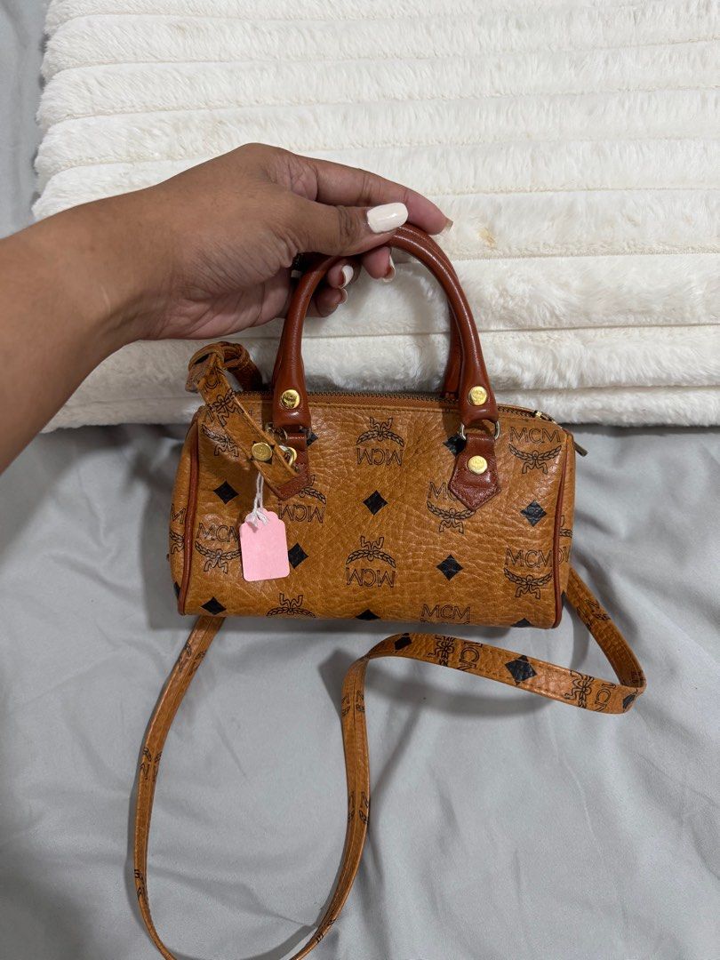 MCM Mini Boston Bag (Category: Luxury Bags & Wallets) located in Baguio. Submitted by luxe2600 (Listing ID 1397972041, Image 2). Description: - Authentic MCM mini Boston bag - Brown exterior with MCM logo pattern - Detachable shoulder strap and top handles - Matching orange interior - Gold-toned hardware - Zipper closure.