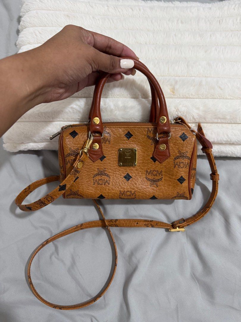 MCM Mini Boston Bag (Category: Luxury Bags & Wallets) located in Baguio. Submitted by luxe2600 (Listing ID 1397972041, Image 1). Description: - Authentic MCM mini Boston bag - Brown exterior with MCM logo pattern - Detachable shoulder strap and top handles - Matching orange interior - Gold-toned hardware - Zipper closure.