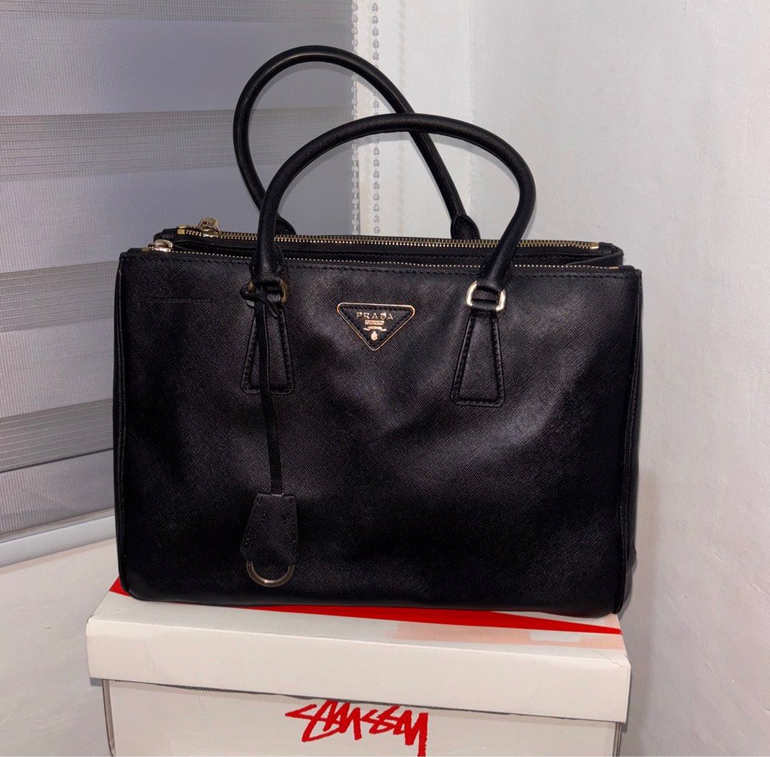 Prada Black Leather Handbag with sling (Category: Luxury Bags & Wallets) located in Bago City. Submitted by christiaaan0515 (Listing ID 1397938845, Image 1). Description: - Black color with gold-tone hardware - Dual top handles and detachable shoulder strap - Interior with multiple compartments - Protective metal feet - In excellent condition.