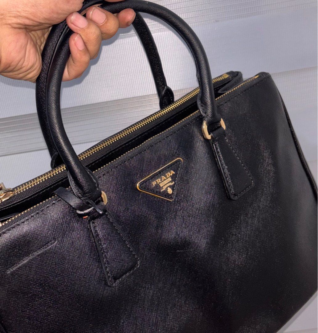 Prada Black Leather Handbag with sling (Category: Luxury Bags & Wallets) located in Bago City. Submitted by christiaaan0515 (Listing ID 1397938845, Image 2). Description: - Black color with gold-tone hardware - Dual top handles and detachable shoulder strap - Interior with multiple compartments - Protective metal feet - In excellent condition.