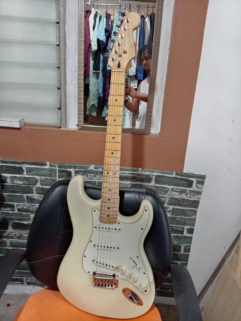 Squier by Fender Stratocaster Electric Guitar (Category: Musical Instruments) located in Agdangan. Submitted by hairulmusicalcolection (Listing ID 1397855074, Image 1). Description: - Squier by Fender Stratocaster - Classic pearl white body - Comfortable maple neck - Equipped with three single-coil pickups - Features a tremolo bridge - Includes volume and tone controls - Authentic Fender headstock with Squier logo - Serial number and "Crafted in 
