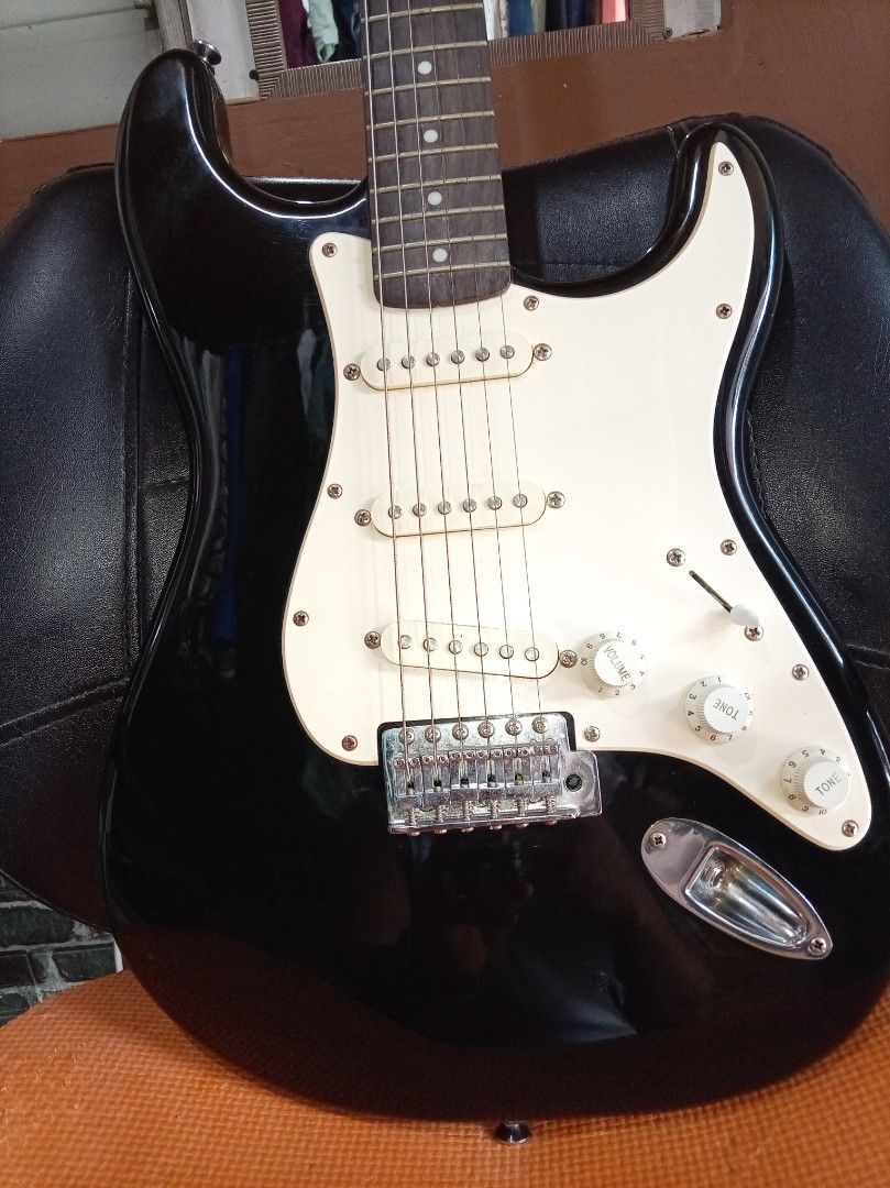 Squier Stratocaster Electric Guitar (Category: Musical Instruments) located in Agdangan. Submitted by hairulmusicalcolection (Listing ID 1397835678, Image 2). Description: - Black Squier Stratocaster electric guitar - White pickguard - Three single-coil pickups - Tremolo bridge - Squier and Fender logos on headstock - Black body with white electronics cover - Maple neck.