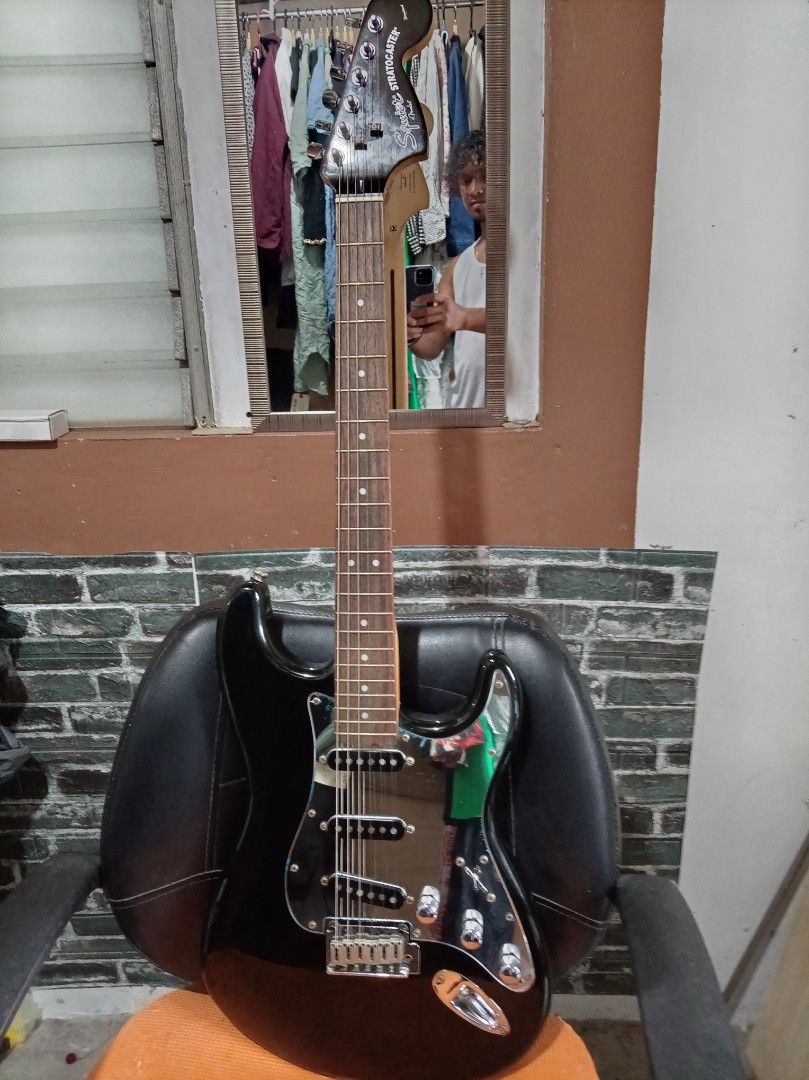 Squier Stratocaster Electric Guitar Standard (Category: Musical Instruments) located in Agdangan. Submitted by hairulmusicalcolection (Listing ID 1397853809, Image 1). Description: - Black Squier Stratocaster electric guitar - Black body with chrome pickguard - Three pickups - Maple neck and fretboard - Squier Stratocaster headstock logo.