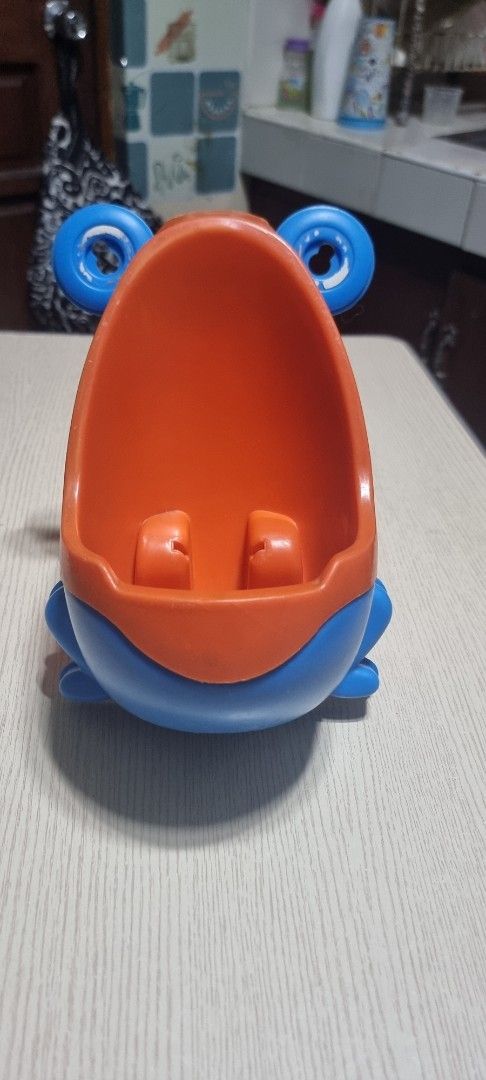 Kids' Frog-Shaped Potty Training Urinal (Category: Toilet Training) located in Marikina City. Submitted by andreah_16 (Listing ID 1398003850, Image 1). Description: - Frog-shaped design - Blue and orange colors - Wide opening for easy use - Includes a splash guard - Made of durable plastic - Easy to clean - Helps with toilet training.