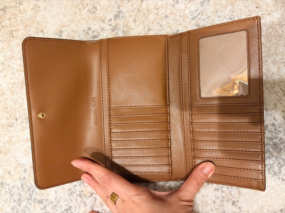 Michael Kors LG Trifold Brown Wallet (Category: Wallets & Card holders) located in Makati City. Submitted by decluttering_28 (Listing ID 1398113397, Image 3). Description: - Authentic Michael Kors LG Trifold wallet -bought in los angeles - Color: Brown - Features: - Multiple card slots - Clear ID window - Zippered compartment - Exterior: Signature MK logo pattern - Closure: Snap - Hardware: Gold-tone metal logo - Includes original receipt - Purch