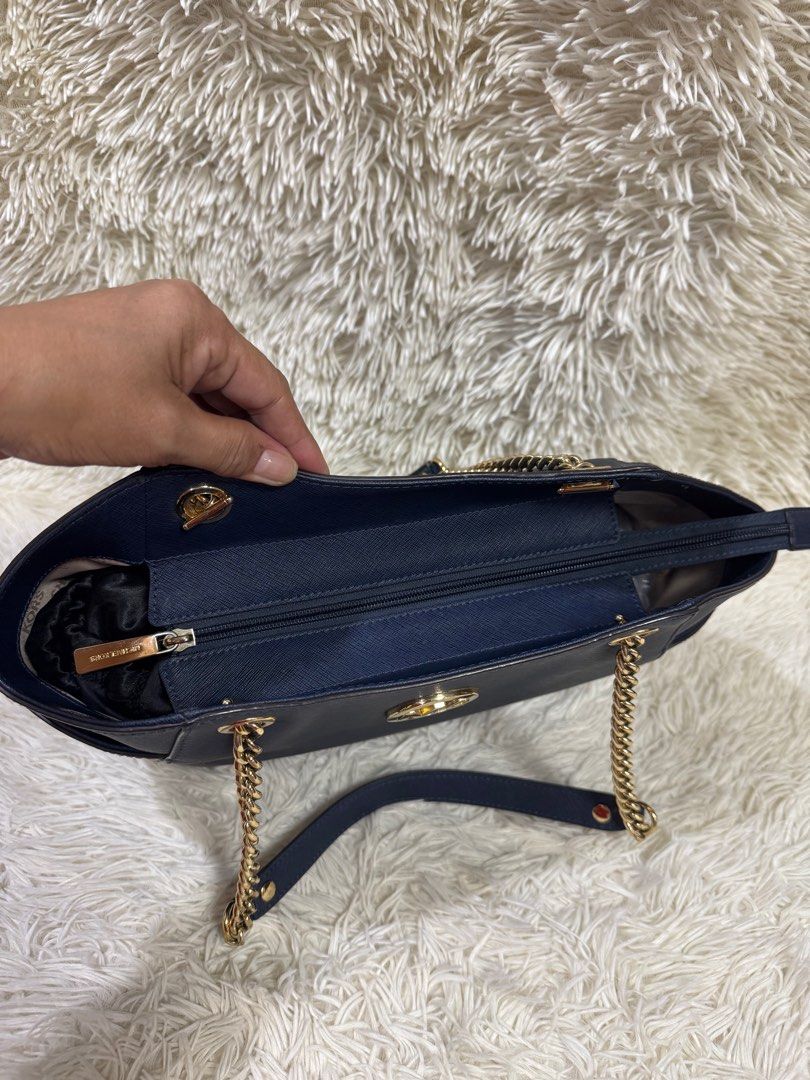 Michael Kors Navy Blue Tote Bag (Category: Luxury Bags & Wallets) located in Rodriguez. Submitted by nancyb13 (Listing ID 1397985011, Image 1). Description: - Michael Kors navy blue tote bag - Gold-tone chain straps - Gold MK logo - Zippered main compartment - Multiple interior pockets - Side pockets - Structured base - Branded interior lining.