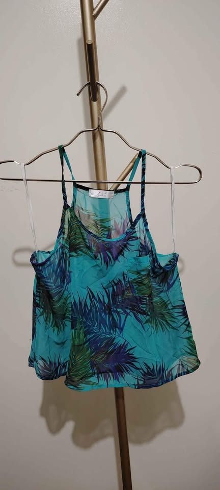 Sheer Tank Top with Tropical Print (Category: Sleeveless) located in Pasay City. Submitted by dollph (Listing ID 1397999045, Image 2). Description: From Hip Culture Can fit up to Large Sheer tank top features a vibrant tropical print in shades of blue and green. It has thin straps and a relaxed fit. The top is lightweight and perfect for warm weather. It is a versatile piece that can be dressed up or down..