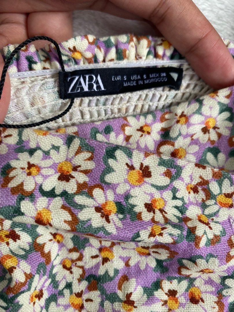 Zara Top (Category: Blouses) located in Cavite. Submitted by jaydaascollection (Listing ID 1398013486, Image 3). Description: Zara floral top with button details. Features a square neckline and thick straps. The top has a daisy print and is made in Morocco. Size S. The top is paired with black shorts in the first image..
