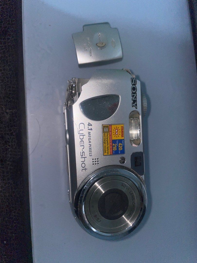 Sony Cyber-shot 4.1MP Digital Camera (Category: Cameras) located in Manila. Submitted by kiagonzale31041 (Listing ID 1398192696, Image 1). Description: - Sony Cyber-shot digital camera - 4.1 megapixels - Silver finish - Model: DSC-P73 - Features a flash - Lens markings: "8-52" - Battery cover is detached -AS IS!! buy on your own risk -camera parts -can lower the price.