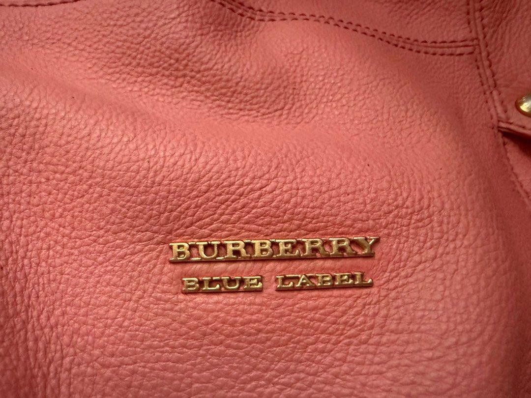 Burberry Blue Label Pink Handbag (Category: Luxury Bags & Wallets) located in Mercedes. Submitted by ddshoping238309 (Listing ID 1398377015, Image 2). Description: - Authentic Burberry Blue Label handbag - Color: salmon pink - Features: - Top handle - Shoulder strap - Plaid lining - Zippered pocket (interior) - Small zipper pocket (exterior) 2 sides - Gold-tone hardware - Snap closure - Brand name visible on the front..