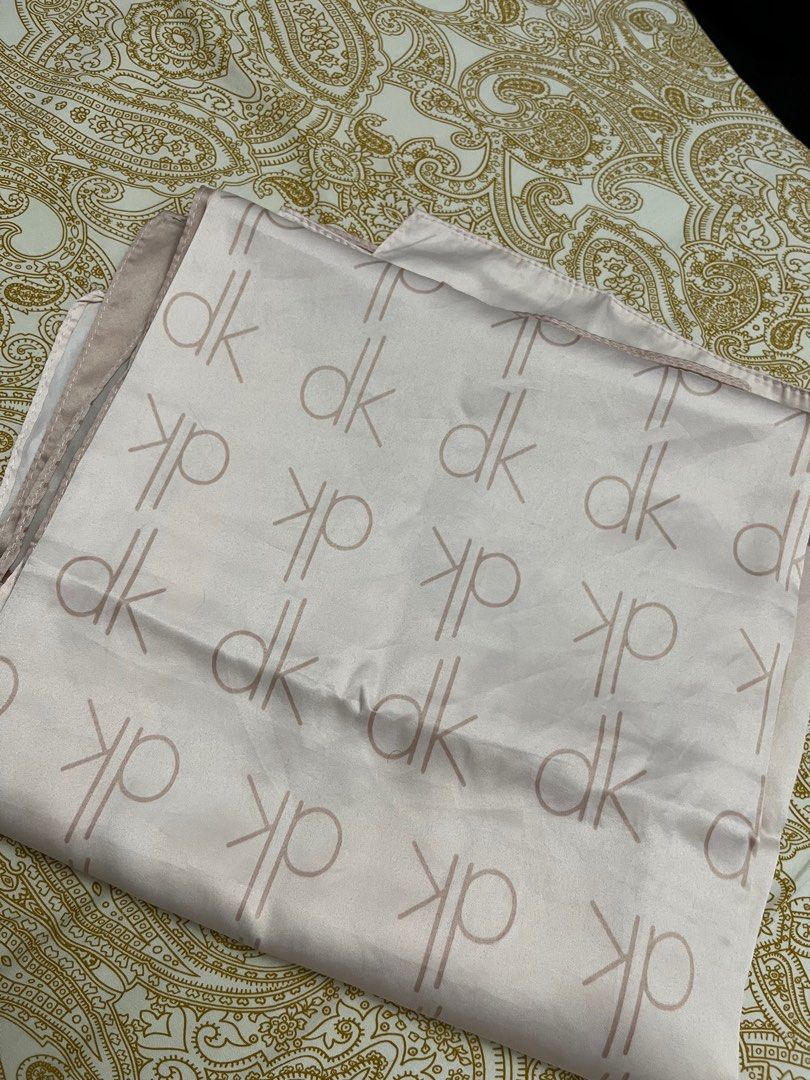 DK Patterned Scarf (Category: Hijabs) located in Kuala Lumpur. Submitted by bungaaprillll (Listing ID 1398458072, Image 1). Description: - Pink scarf with a 'dk' pattern - Brown border and accents - Made of a smooth, silky material - Rectangular shape - Can be styled in multiple ways.