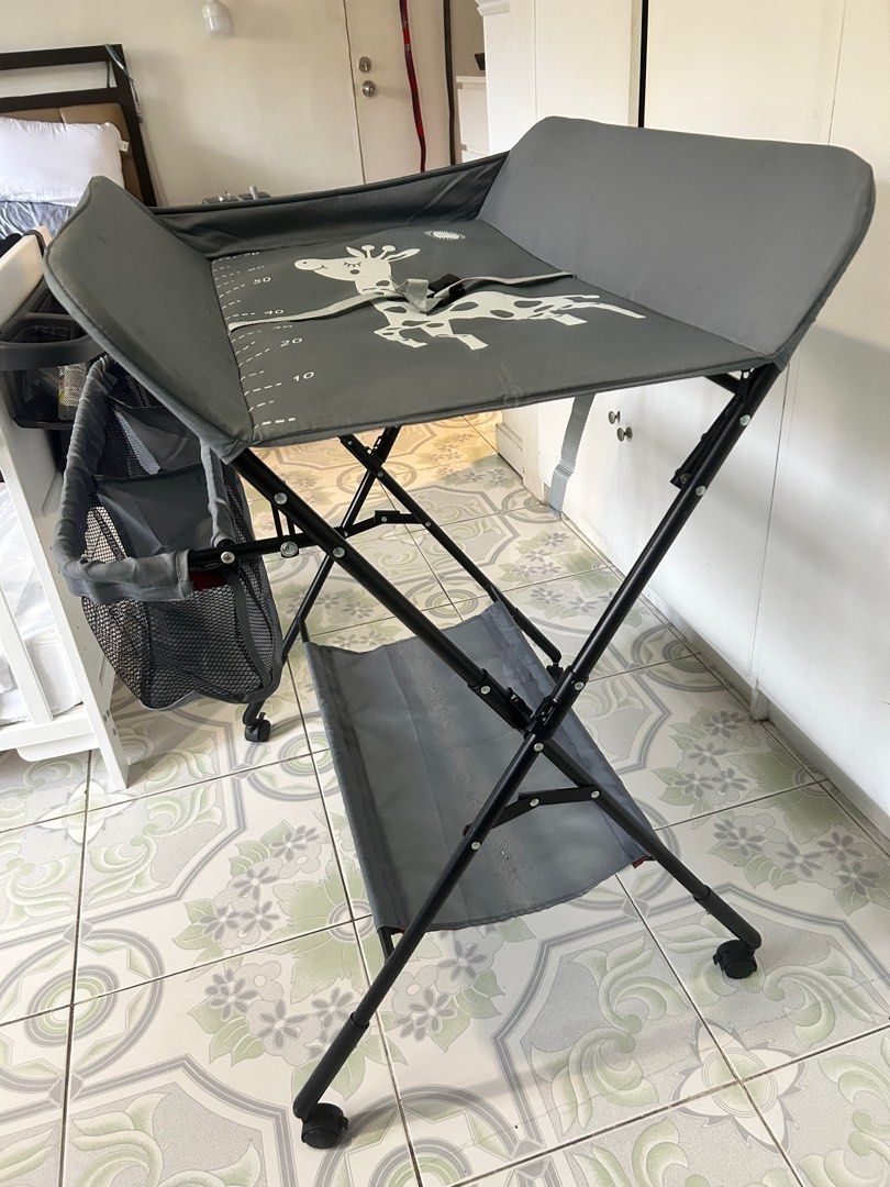 Foldable Baby Changing Table with Giraffe Design (Category: Changing Mats & Accessories) located in San Pedro. Submitted by ukaynikukay (Listing ID 1398412789, Image 3). Description: - Built-in measuring guide - Includes safety strap - Storage basket for essentials - Lower shelf for extra storage - Sturdy, foldable frame - Wheels for easy movement and locks - Collapsible for easy storage - Up to 15kg capacity.