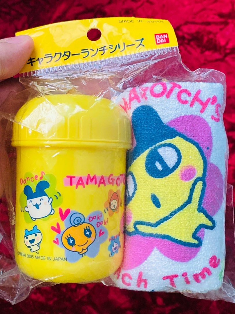 Tamagotchi Face towel with container set 280 (Category: Food Organization & Storage) located in Zamboanga. Submitted by kawaii_omocha_est2020 (Listing ID 1398402364, Image 2). Description: - Authentic Tamagotchiface towel witj container set (Made in Japan). - Includes a yellow container and matching towel. - Lunch box features Tamagotchi characters and "Lunch Time" text. - Towel features a large Tamagotchi character and "Tamagotchi's Lunch Time" 