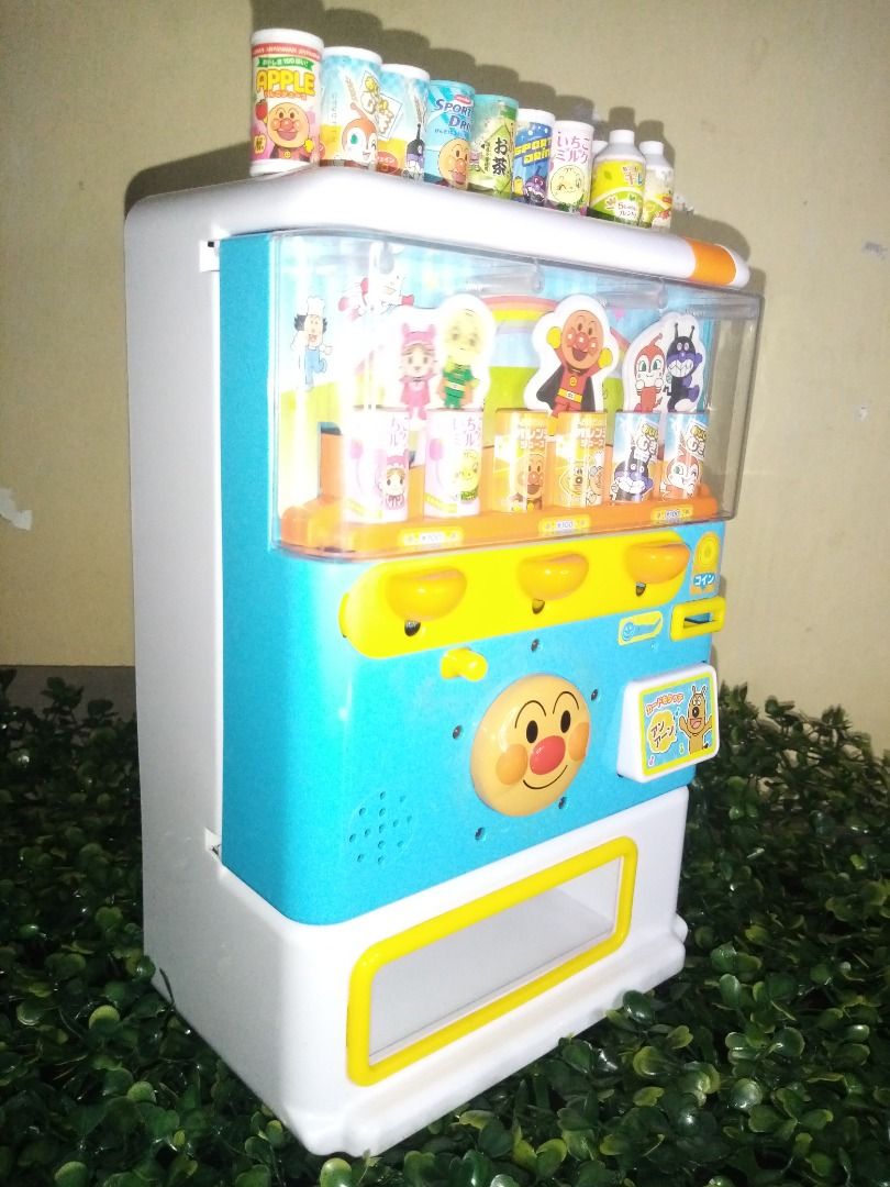 Anpanman Toy Vending Machine (Category: Designer & Blind Box Toys) located in Tanza. Submitted by leonskidskorner (Listing ID 1398579869, Image 3). Description: - Anpanman-themed toy vending machine - Includes juice dispensers - Comes with miniature drink cans - Features a blue and white design with Anpanman characters - Has a small refrigerator compartment - Includes a coin slot and dispensing area - Perfect for imaginative play!.