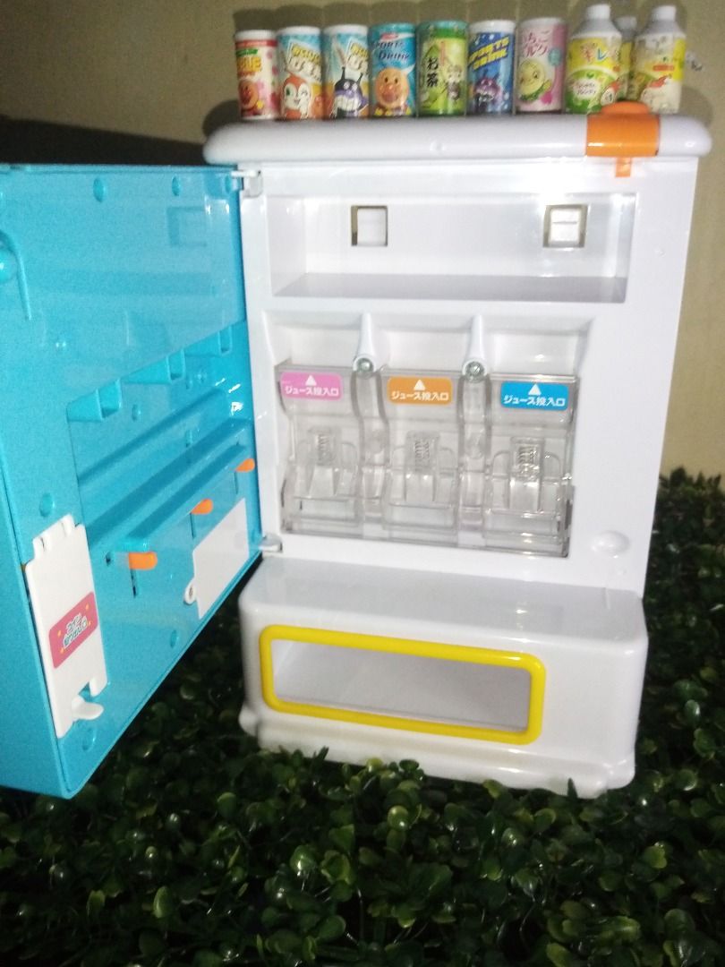 Anpanman Toy Vending Machine (Category: Designer & Blind Box Toys) located in Tanza. Submitted by leonskidskorner (Listing ID 1398579869, Image 2). Description: - Anpanman-themed toy vending machine - Includes juice dispensers - Comes with miniature drink cans - Features a blue and white design with Anpanman characters - Has a small refrigerator compartment - Includes a coin slot and dispensing area - Perfect for imaginative play!.