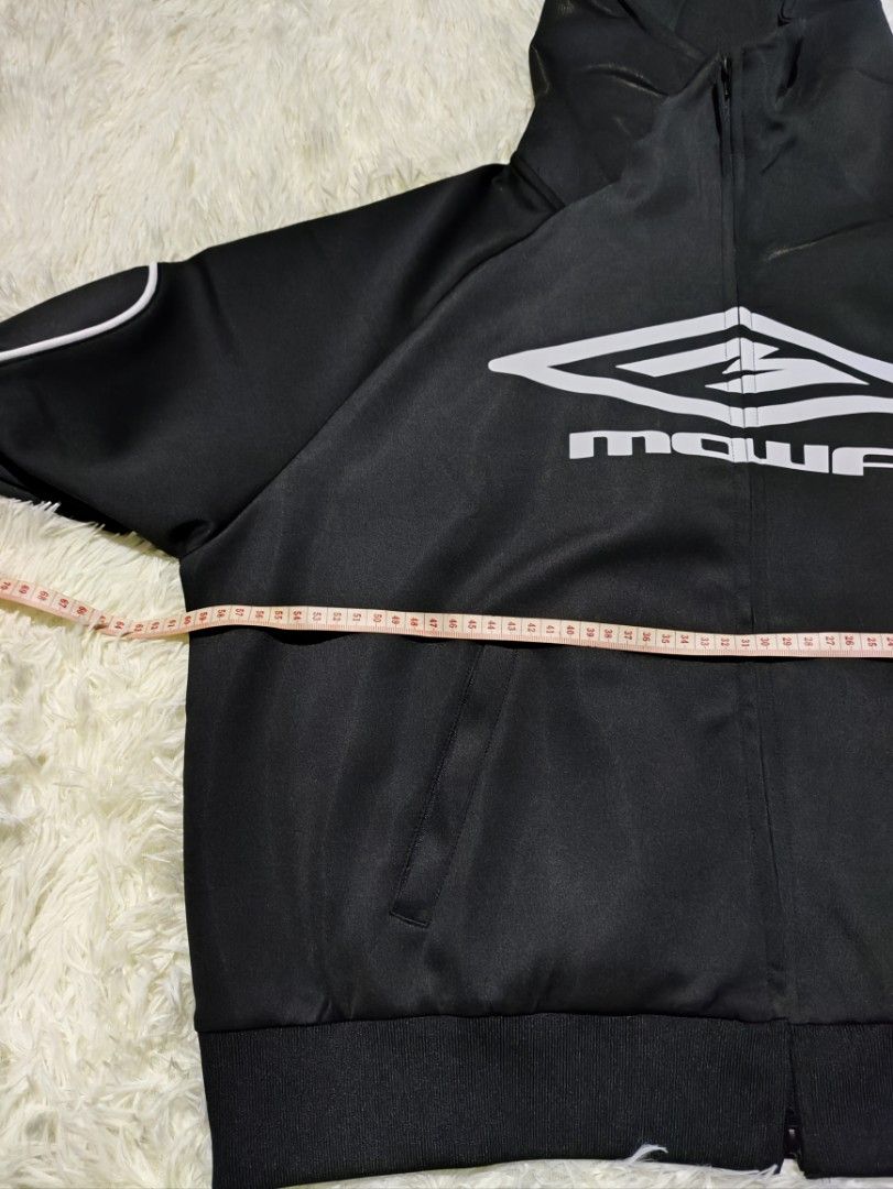 Mowalola Black Hoodie Jacket (Category: Coats, Jackets and Outerwear) located in Caloocan City. Submitted by 808akali (Listing ID 1398675976, Image 3). Description: Black hoodie jacket from Mowalola. Features a full zip closure, hood, and white accents along the sleeves. The Mowalola logo is prominently displayed on the front. The jacket is size S and made of a polyester and spandex blend. The jacket has a ribbed hem and cuffs..