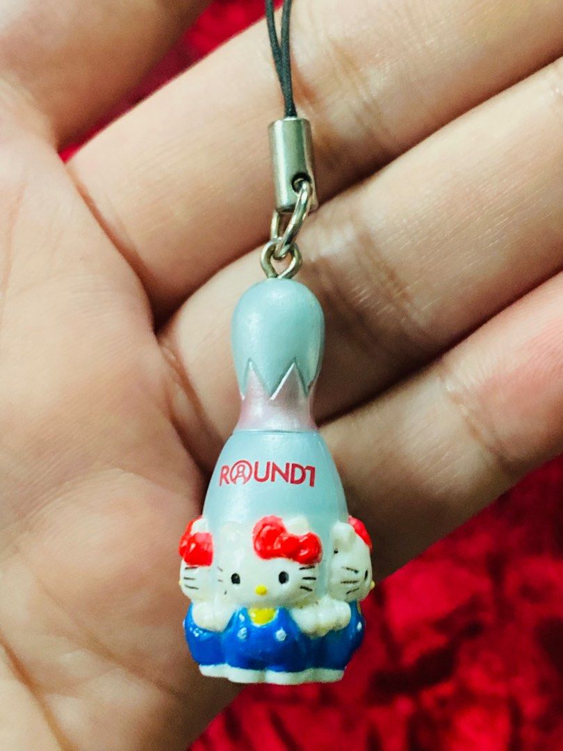 Hello Kitty Round 1 Bowling Pin Keychain 250 (Category: Character Goods) located in Zamboanga. Submitted by kawaii_omocha_est2020 (Listing ID 1398823873, Image 2). Description: - Adorable Kitty bowling pin keychain. - Features a silver top and blue base. - Decorated with Kitty faces. - Marked with 'Round 1' and the Sanrio logo. - Comes with a black strap for easy attachment. ✅Mine now/ Pay now ✅ Please scan all photos for more details. ✅ Manage y