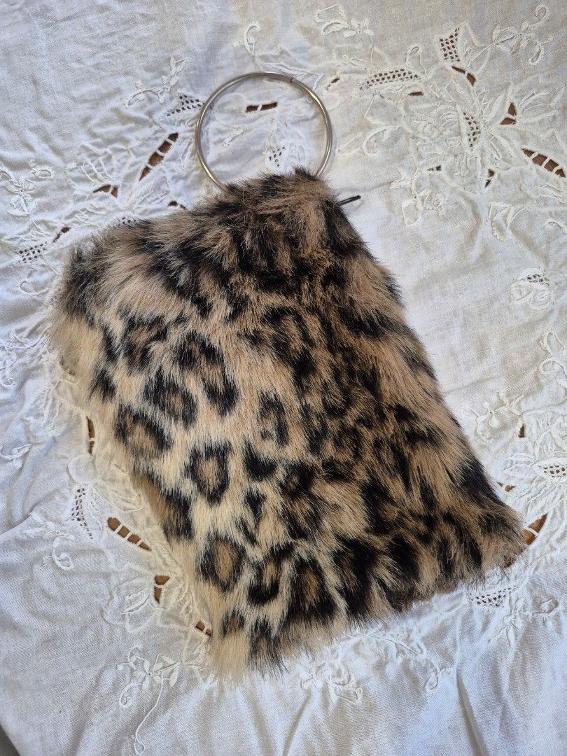 Leopard Print Clutch with Ring Handle (Category: Clutches) located in Quezon City. Submitted by soaring7 (Listing ID 1398786974, Image 1). Description: Faux fur. Clutch features a striking leopard print design. It has a ring handle for easy carrying. The interior is lined with black fabric and includes a zipper closure. The clutch is compact and stylish, perfect for carrying essentials. It's a unique accessory that adds a touch of flair to any ou