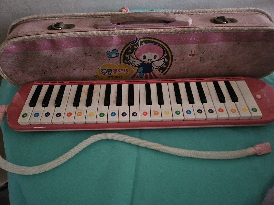 Pink Melodica with Case (Category: Musical Instruments) located in Quezon City. Submitted by lizawoo (Listing ID 1398790016, Image 1). Description: - Pink melodica with matching case and mouthpiece. - Keyboard with colored keys. - Includes a white, flexible tube. - Case has a handle and a front design. - Melodica is in good working condition. from Korea.