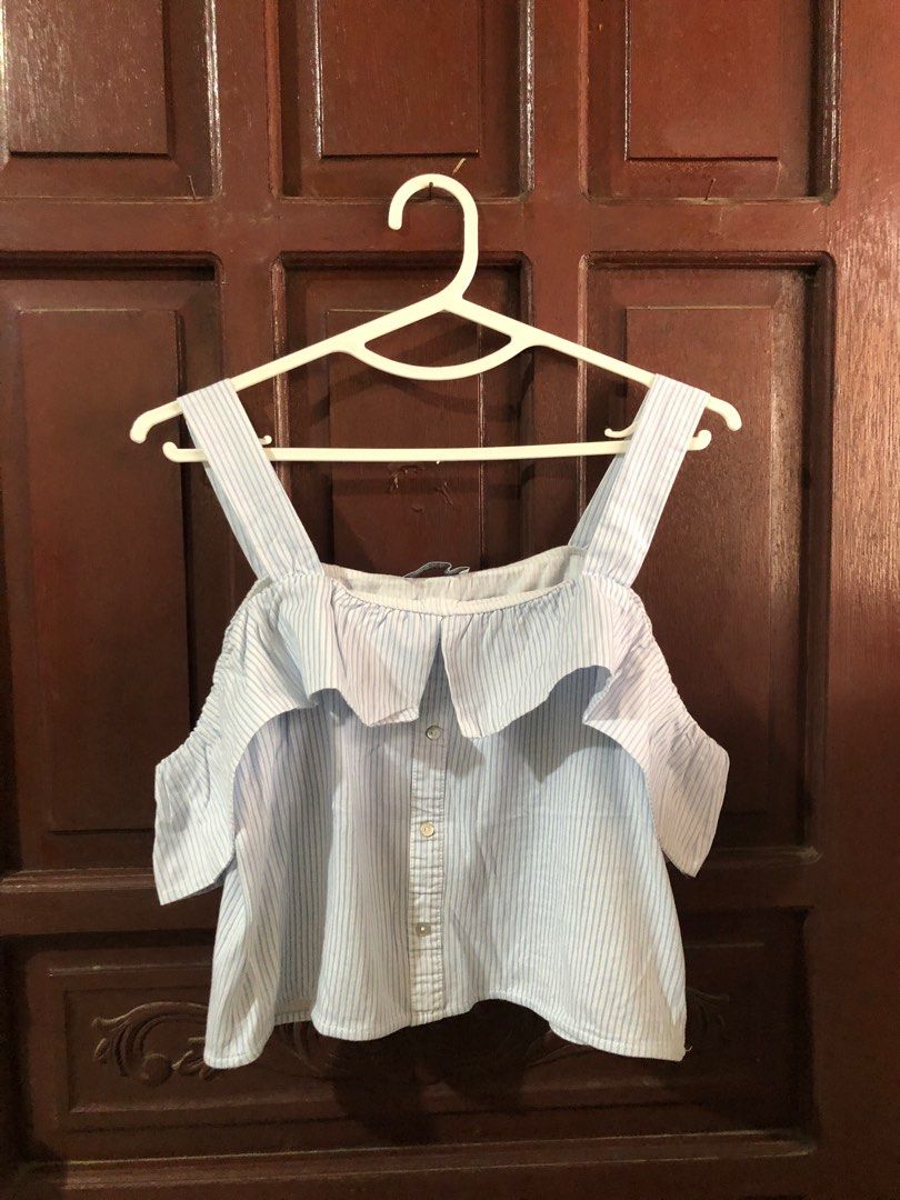 Zara Trafaluc Off-Shoulder Top (Category: Blouses) located in Bacoor. Submitted by declutteredbygem (Listing ID 1398704646, Image 1). Description: - Zara Trafaluc off-shoulder top - Striped pattern - Ruffled neckline - Button-down front - Color: Light blue and white - Size: S/36 (EUR/USA 26) - Made in Morocco.