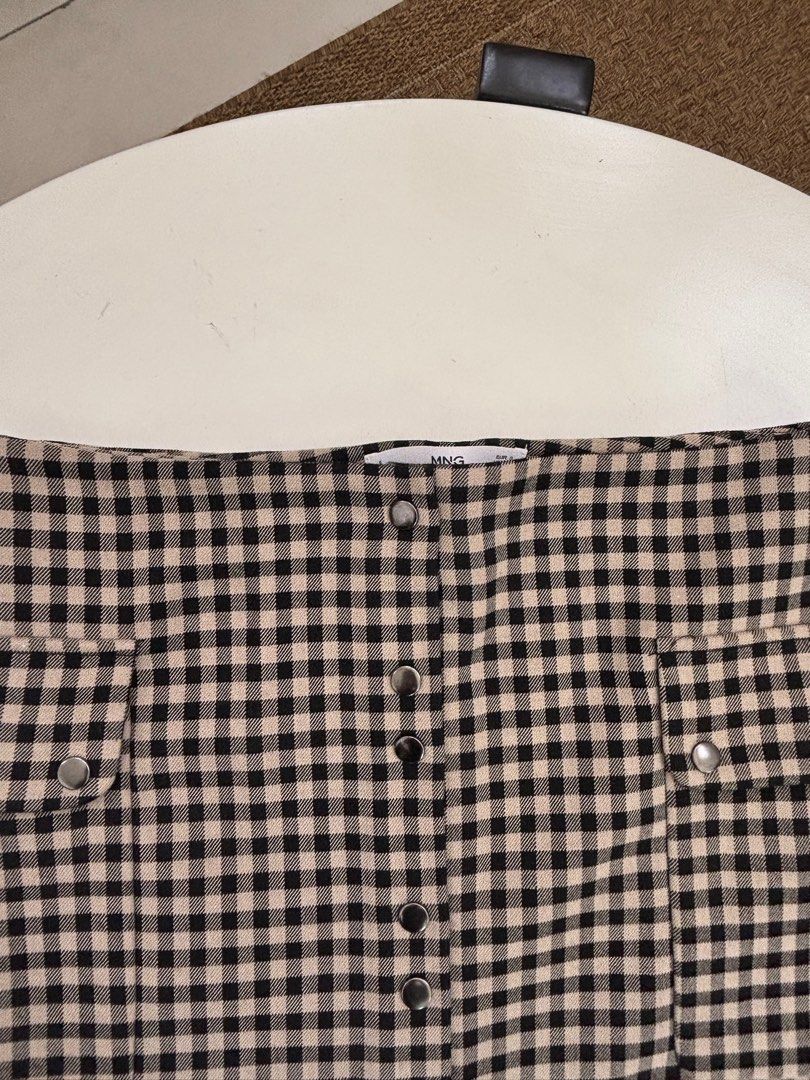 Mango Casual Checkered Skirt (Category: Skirts) located in Rodriguez. Submitted by alekshivers (Listing ID 1398881638, Image 3). Description: - MNG Casual skirt - Checkered pattern (black and beige) - Button-down style - Features two pockets - Size: XS - Perfect for a casual and chic look.