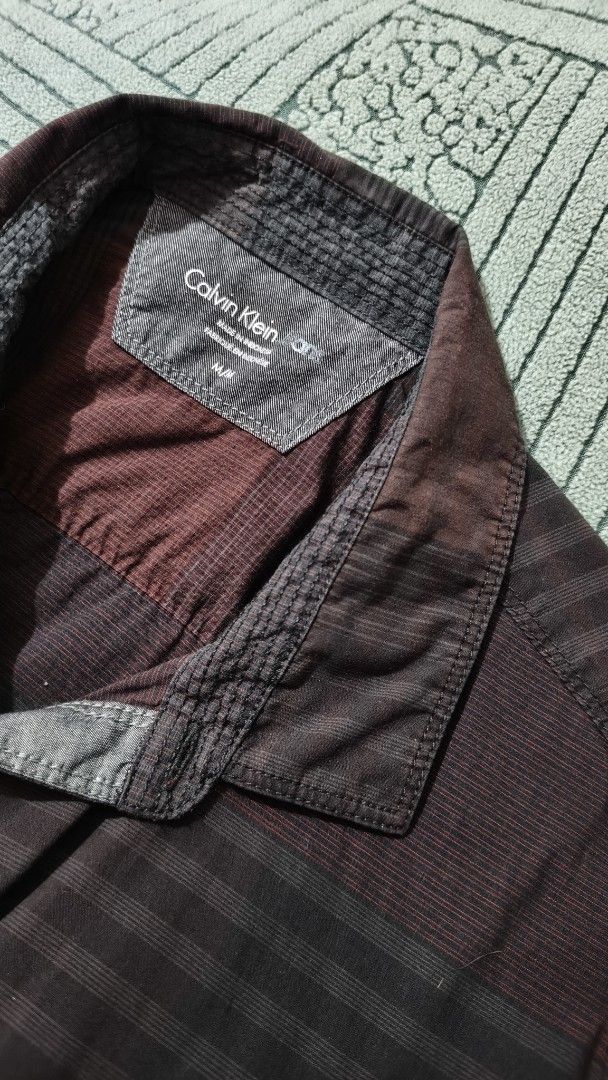 Calvin Klein Jeans Striped Shirt (Category: Shirts) located in Rizal. Submitted by declutterwithliz (Listing ID 1399121003, Image 2). Description: - Calvin Klein Jeans shirt - Size: M/P - Color: Maroon - Pattern: Striped - Features: Collared neckline, long sleeves - Design: Classic - Suitable for various occasions.