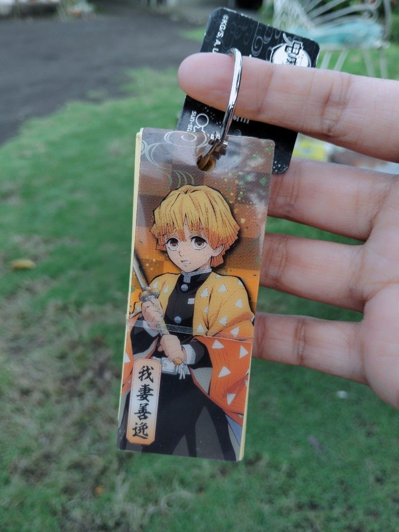 Demon Slayer Zenitsu Keychain (Category: Character Goods) located in Ligao. Submitted by jmcollcxxxxn (Listing ID 1399057716, Image 1). Description: - Features Zenitsu from Demon Slayer. - Rectangular keychain design. - Clear protective layer. - Durable metal ring. - Back design: Stack of pages. - Ideal for Demon Slayer fans..