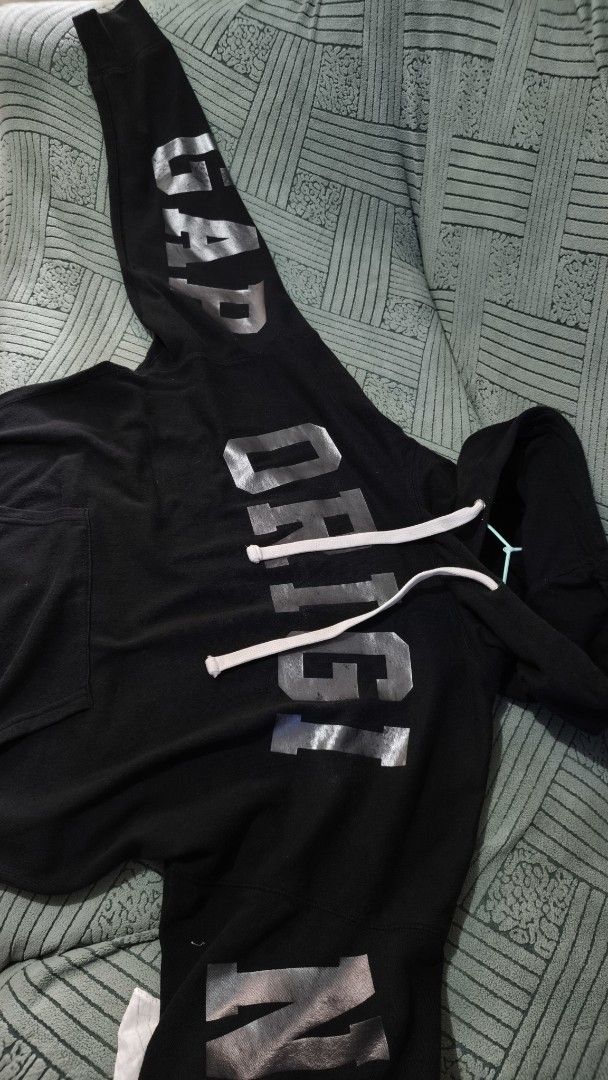 GAP Black Hoodie with Silver Print (Category: Hoodies) located in Rizal. Submitted by declutterwithliz (Listing ID 1399093817, Image 2). Description: - Black hoodie - Silver "ORIGI" and "ORIGINAL" print - Hood with white drawstrings - Front pocket - Silver print on sleeves - Casual and comfortable.