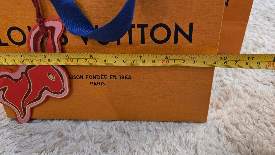 Louis Vuitton Small sized Paper Bags (Category: Luxury Bags & Wallets) located in Paranaque City. Submitted by karenmn (Listing ID 1399143885, Image 2). Description: Authentic Louis Vuitton paper bags - Includes three orange bags with blue handles - Features the iconic Louis Vuitton logo - 2 sizes, pls see photos for exact measurements - 1 bag features the Zodiac CNY year of the rabbit edition bag charm Selling as a set. Asking: Php 1,800 + sf MO