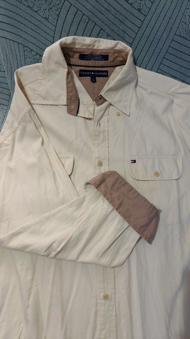 Tommy Hilfiger Long Sleeve Shirt (Category: Tshirts & Polo Shirts ) located in Rizal. Submitted by declutterwithliz (Listing ID 1399095775, Image 1). Description: - Tommy Hilfiger long sleeve shirt - Button-down style - Collared neckline - Features two chest pockets - Buttoned cuffs - Beige body with brown collar and cuff accents - Tommy Hilfiger logo on collar.
