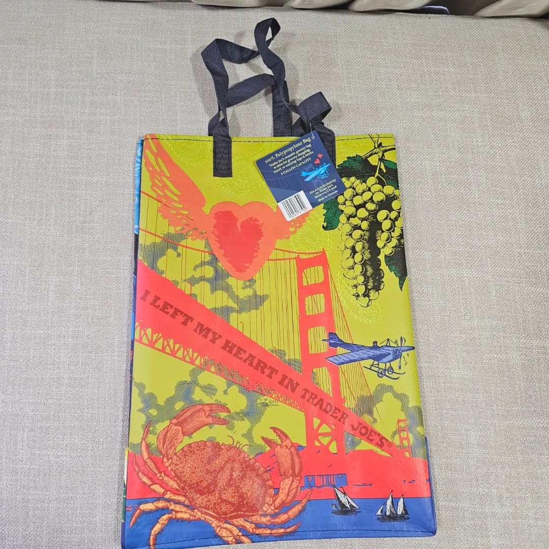Trader Joe's Reusable Shopping Bag (Category: Tote Bags) located in Mandaluyong City. Submitted by cleanhouse.ph (Listing ID 1395988434, Image 2). Description: - Trader Joe's reusable shopping bag - Colorful blue and yellow design - Features various illustrations - Includes handles for easy carrying - Made of durable, reusable material - Perfect for groceries and everyday use.