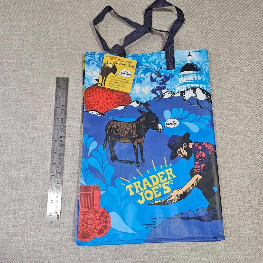 Trader Joe's Reusable Shopping Bag (Category: Tote Bags) located in Mandaluyong City. Submitted by cleanhouse.ph (Listing ID 1395988434, Image 3). Description: - Trader Joe's reusable shopping bag - Colorful blue and yellow design - Features various illustrations - Includes handles for easy carrying - Made of durable, reusable material - Perfect for groceries and everyday use.