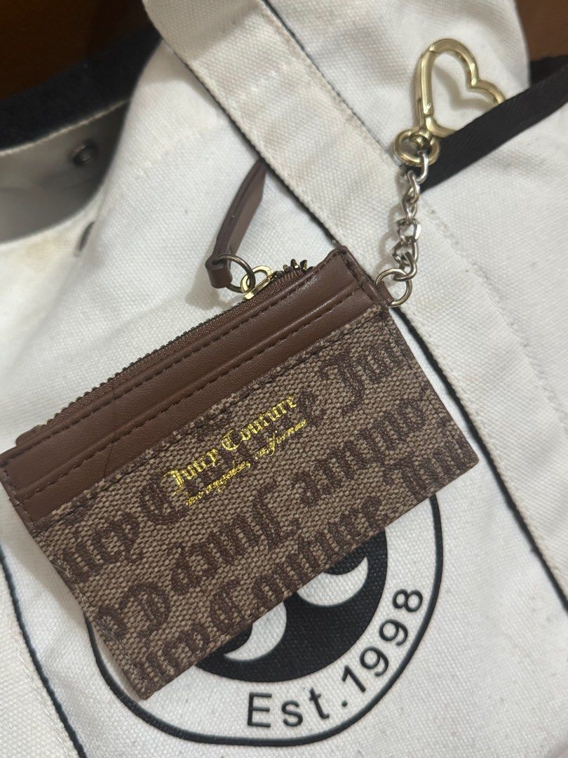 Juicy Couture Cardholder with Keychain (Category: Wallets & Card holders) located in Taguig. Submitted by bncdnc (Listing ID 1399334942, Image 1). Description: - Authentic Juicy Couture cardholder - Brown and tan design - Includes a zippered compartment - Multiple card slots for organization - Comes with a gold-toned heart-shaped keychain - Interior lining with Juicy Couture logo - Perfect for cards and small essentials.