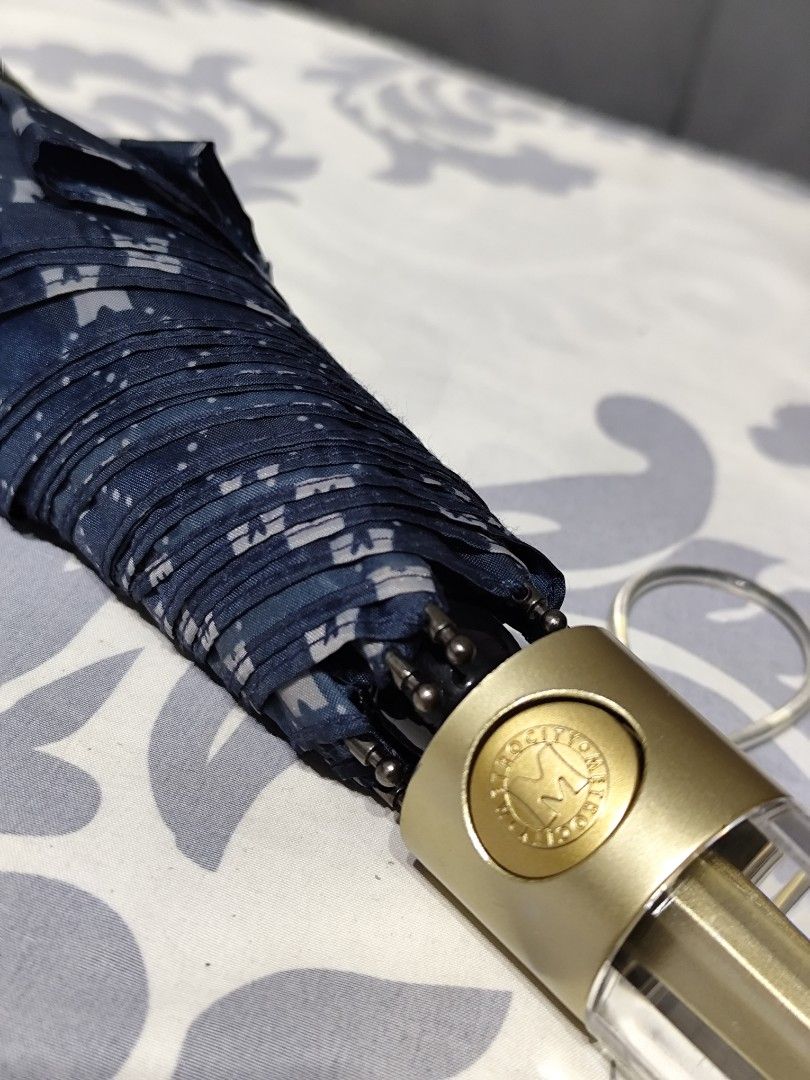 Metrocity Folding Umbrella (Category: Umbrellas) located in Santa Rosa. Submitted by ahroncatpad (Listing ID 1399431590, Image 3). Description: - Metrocity folding umbrella -automatic - Navy blue and white pattern - Gold handle with clear plastic detail - Includes Metrocity logo - Folds up for easy storage.