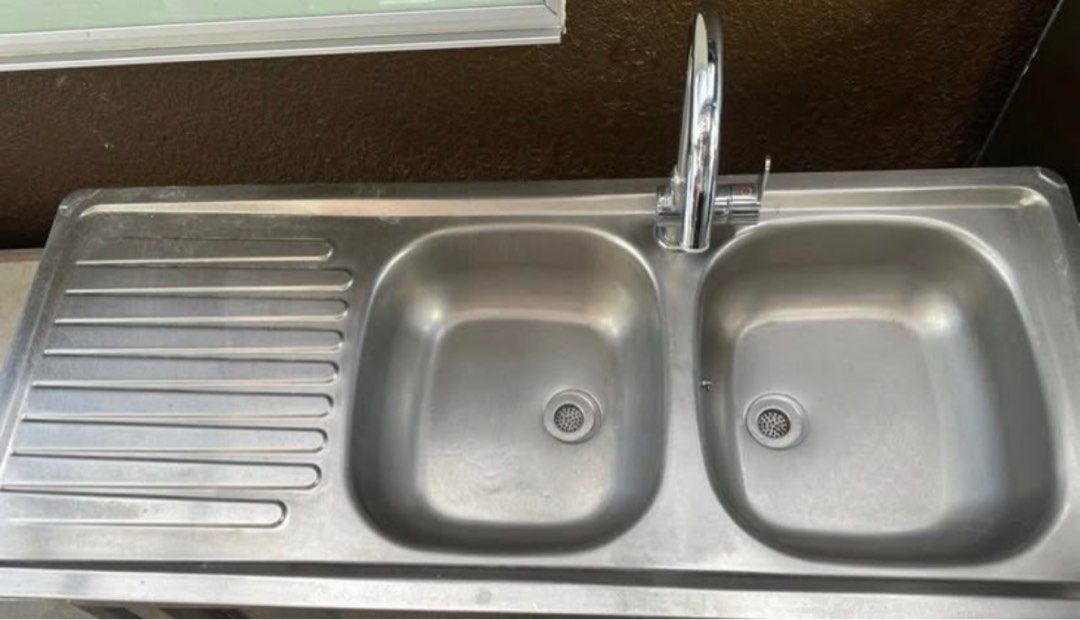 Stainless Steel Double Bowl Kitchen Sink (Category: Bathroom & Kitchen Fixtures) located in Quezon City. Submitted by tinylee60 (Listing ID 1399443850, Image 1). Description: - Stainless steel double bowl kitchen sink - Includes built-in drainboard - Comes with a chrome faucet - Features two basins for convenience - Ideal for kitchen use.
