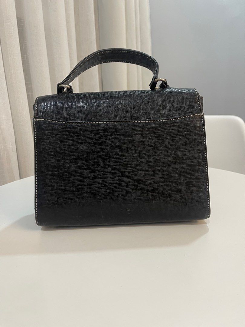 Vintage Moschino Black Handbag (Category: Luxury Bags & Wallets) located in Makati City. Submitted by triftedandbranded (Listing ID 1399383786, Image 3). Description: - Moschino black handbag - Top handle - Flap closure with gold-tone logo plaque - Interior lining with repeating Moschino logo pattern - White stitching details - Made of textured leather-like material.
