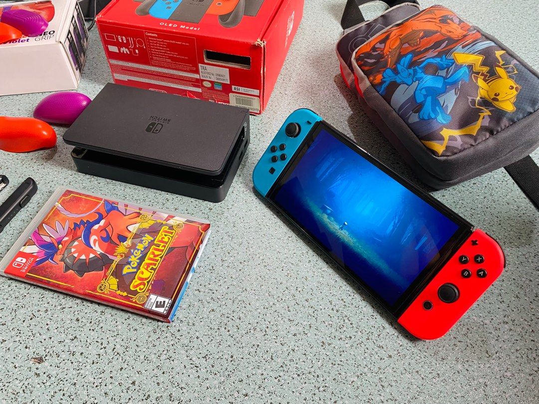 Nintendo Switch OLED Model Bundle (Category: Nintendo) located in Sorsogon. Submitted by m.espedido (Listing ID 1399460389, Image 2). Description: - Nintendo Switch OLED Model with red and blue Joy-Cons - Includes Pokemon Scarlet game - Pokemon-themed carrying case - Charging dock included - Comes with a Neo Grip - Includes Joy-Con straps - Original box included.