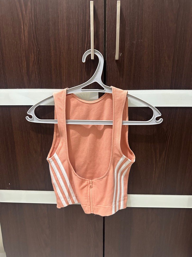 [ADIDAS] Crop Top with Zipper (Category: Others Tops) located in Manila. Submitted by abcdeclutter__ (Listing ID 1399727287, Image 2). Description: - Adidas crop top in peach - Ribbed texture - Small Adidas logo - Low scoop back - White stripes on sides - Front zipper closure - Stylish and comfortable.