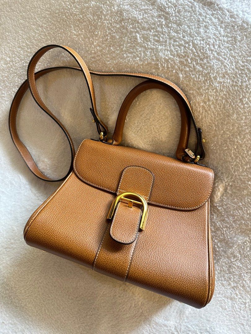 Delvaux Brown Leather Handbag (Category: Luxury Bags & Wallets) located in Jagna. Submitted by gemts777 (Listing ID 1399809735, Image 2). Description: - Cognac leather handbag - Structured design - Top handle and detachable shoulder strap - Gold-tone buckle closure - Protective feet - White stitching.