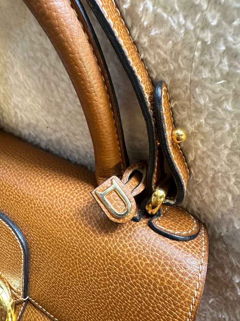 Delvaux Brown Leather Handbag (Category: Luxury Bags & Wallets) located in Jagna. Submitted by gemts777 (Listing ID 1399809735, Image 3). Description: - Cognac leather handbag - Structured design - Top handle and detachable shoulder strap - Gold-tone buckle closure - Protective feet - White stitching.