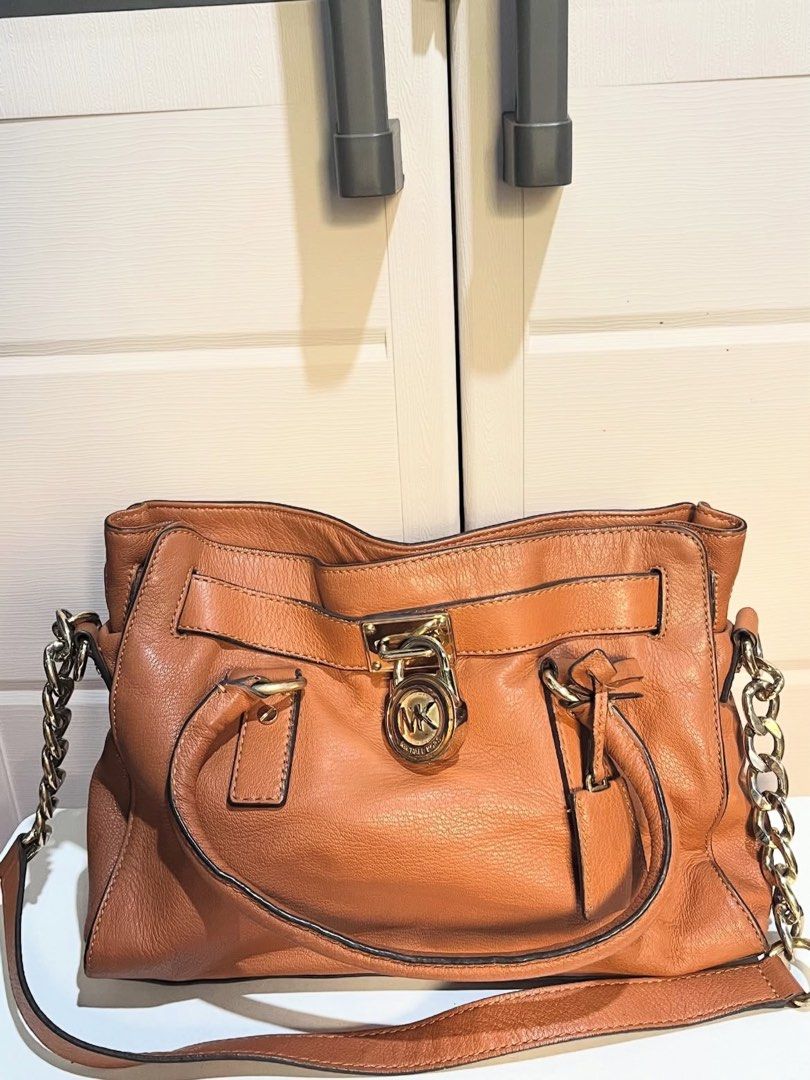 Michael Kors Hamilton Satchel Bag (Category: Luxury Bags & Wallets) located in Agoo. Submitted by grandtree-2c14 (Listing ID 1399651853, Image 1). Description: - Authentic Michael Kors Hamilton satchel bag - Brown leather exterior - Gold-tone hardware - Top handle and detachable shoulder strap - Signature MK fabric lining - Multiple interior compartments - MK logo lock closure - Stylish chain detailing.