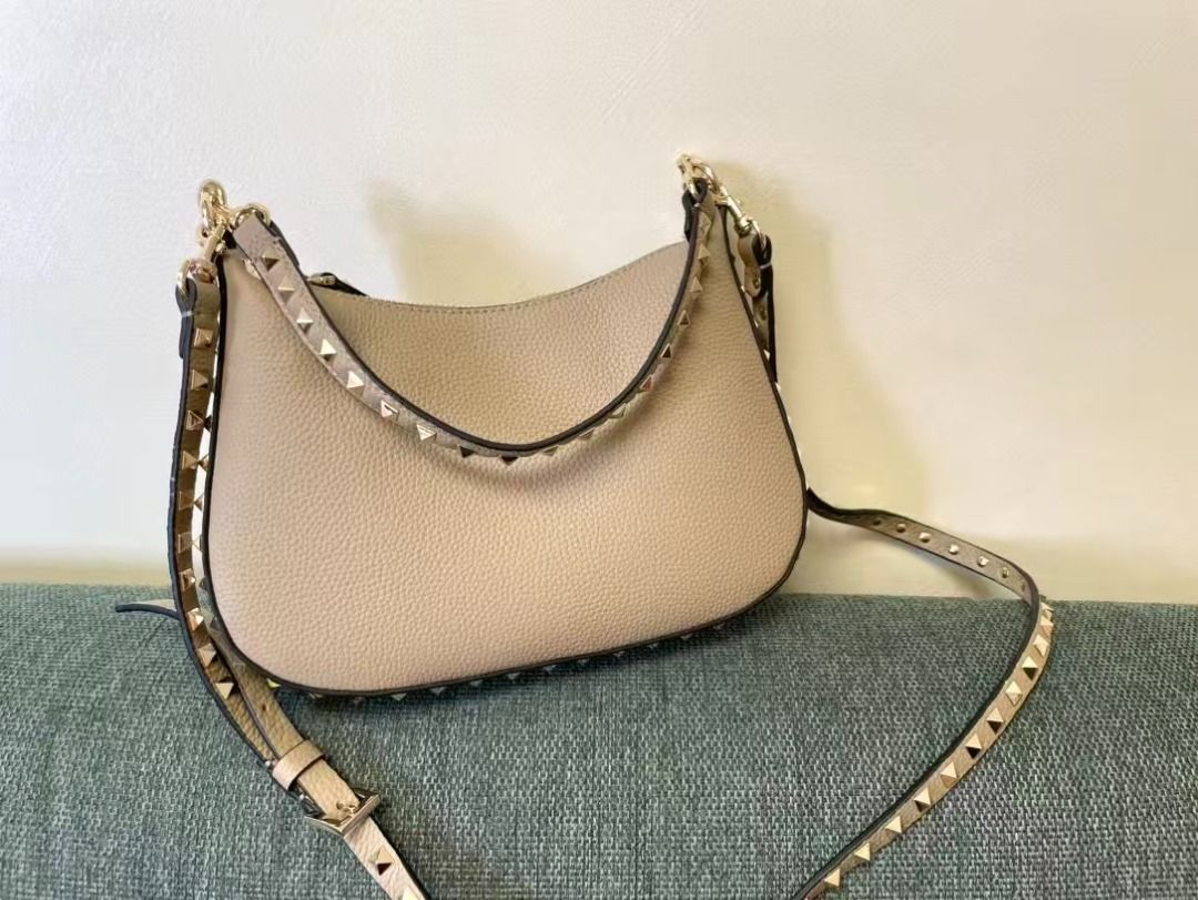 Valentino Garavani Rockstud Hobo Bag (Category: Luxury Bags & Wallets) located in Muntinlupa City. Submitted by azuomaigor72472 (Listing ID 1399709423, Image 1). Description: - Valentino Garavani Rockstud Hobo Bag - Beige leather exterior - Gold-tone hardware - Studded shoulder strap - Top handle - Curved shape - Zip closure.