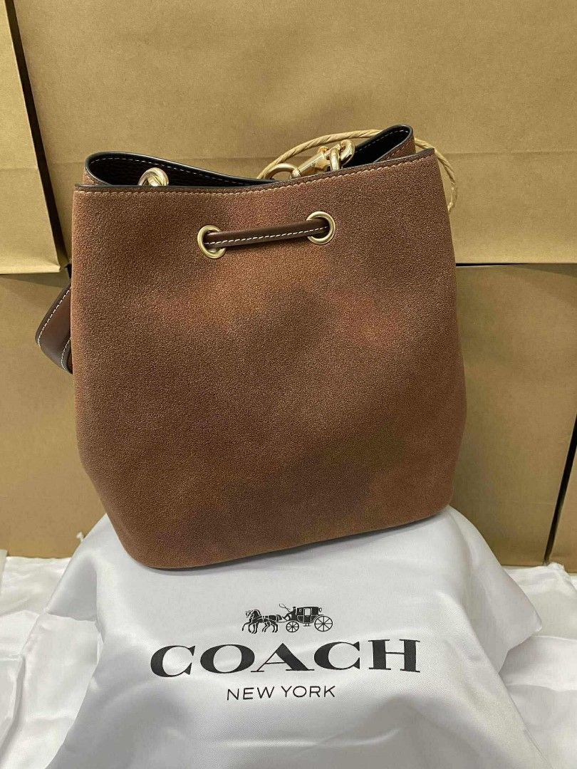 Coach Rowan Bucket (Category: Luxury Bags & Wallets) located in Batangas. Submitted by YSABELLE_MARGARETTE (Listing ID 1399987512, Image 3). Description: - Coach bucket bag - Brown suede - Detachable strap & pouch included - Drawstring closure - Gold-tone hardware - Dimensions: Approx. 22 x 21.5 cm - Includes Coach dust bag, paperbag, card, receipt & individual plastic.