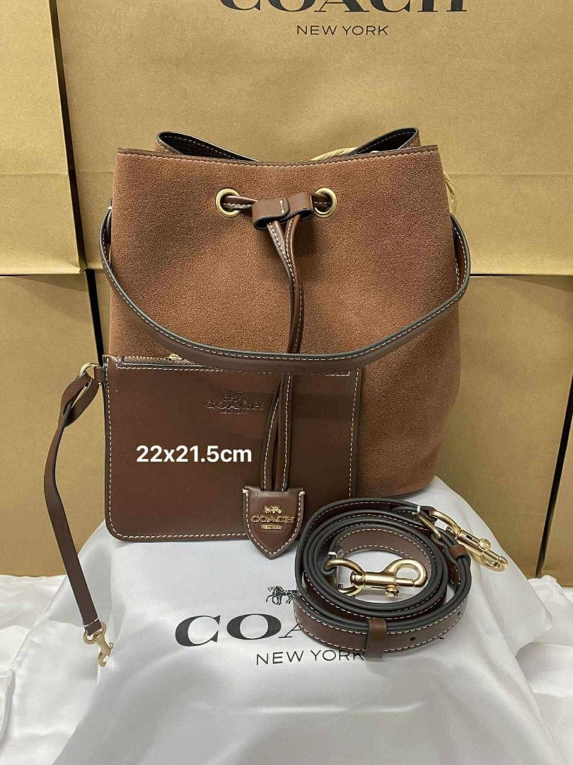 Coach Rowan Bucket (Category: Luxury Bags & Wallets) located in Batangas. Submitted by YSABELLE_MARGARETTE (Listing ID 1399987512, Image 1). Description: - Coach bucket bag - Brown suede - Detachable strap & pouch included - Drawstring closure - Gold-tone hardware - Dimensions: Approx. 22 x 21.5 cm - Includes Coach dust bag, paperbag, card, receipt & individual plastic.