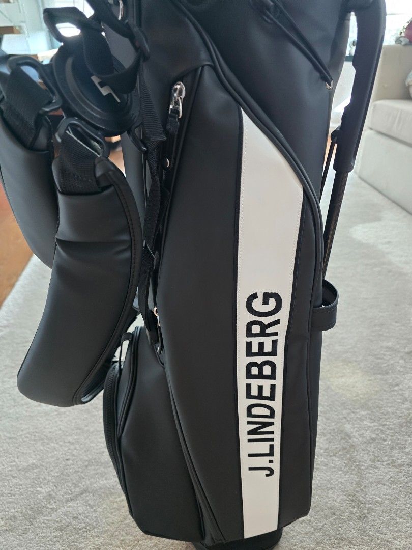 J. Lindeberg Sunday Stand Golf Bag (Category: Golf) located in Makati City. Submitted by dpadill (Listing ID 1399832214, Image 1). Description: - J. Lindeberg black golf bag - Sunday Stand bag design - Features multiple compartments - Includes a stand for easy use - Comes with a shoulder strap - Vessel logo on the base - Ideal for a quick round of golf.