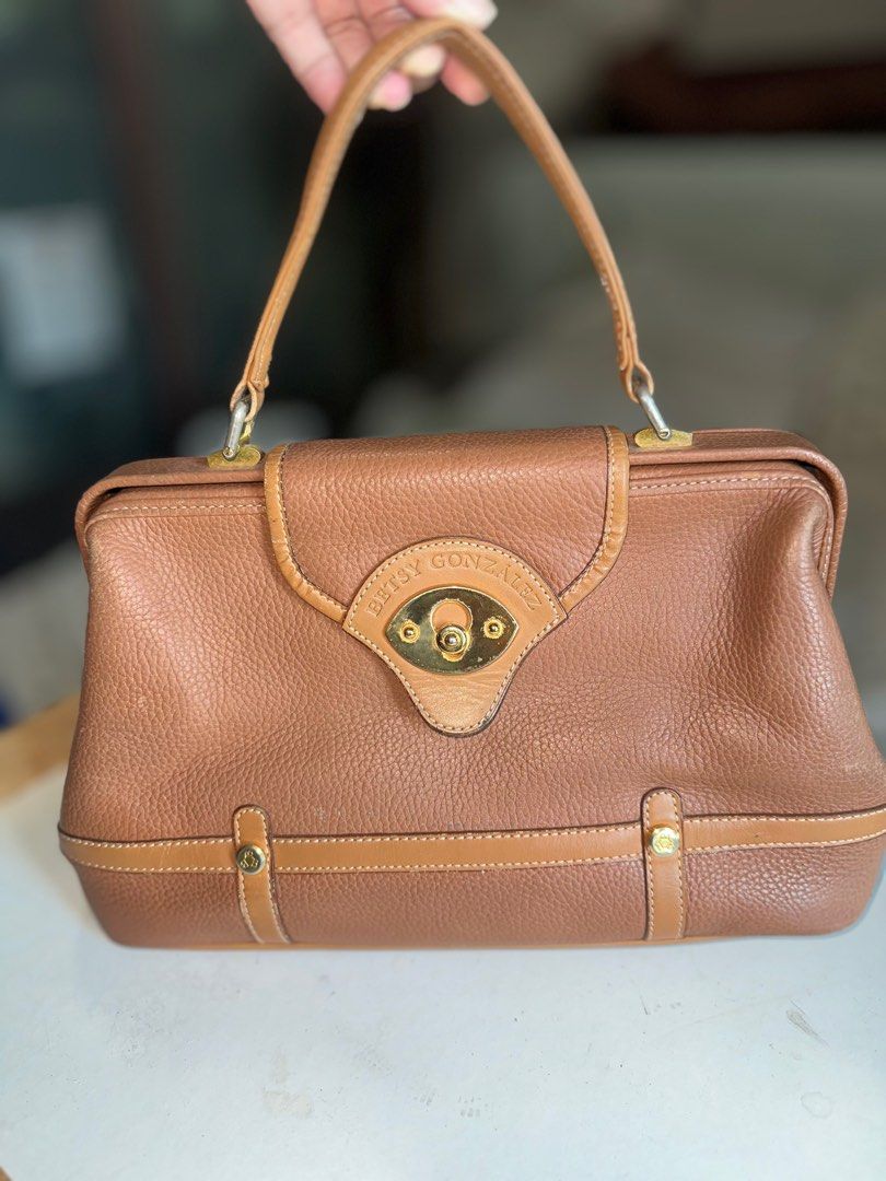 Betsy Gonzalez Boston Bag (Category: Luxury Bags & Wallets) located in Mandaluyong City. Submitted by TheWeekendProject (Listing ID 1400064602, Image 1). Description: Betsy Gonzalez New York Brown Leather Doctors Bag Top Handle Bag. Gladstone opening. Gold hardware. Outer zipper pocket and inner pockets. Pu Leather lining needs cleaning. Normal signs of use. Size 11” x 8” x 5” Base 13” Pickup Mandaluyong.