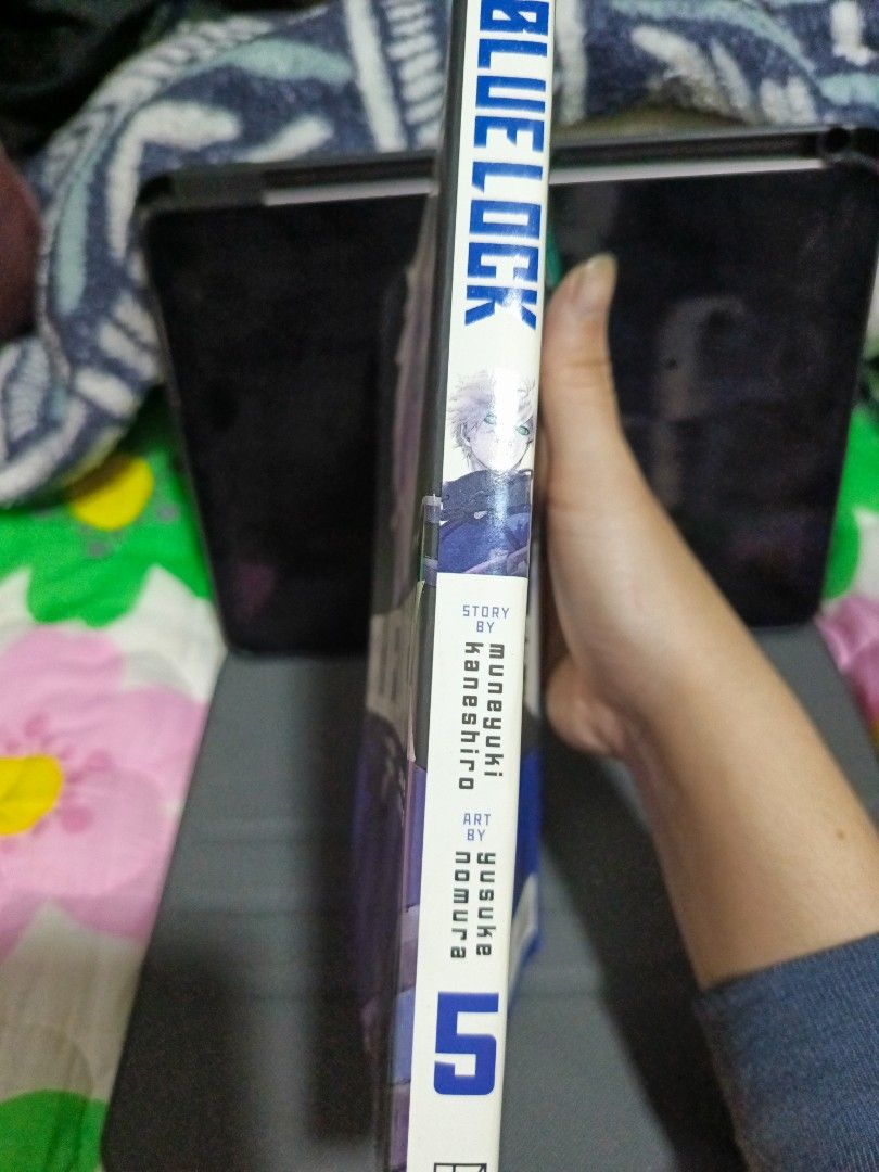 Blue Lock Manga Volume 5 (Category: Comics & Manga) located in Tacloban City. Submitted by lex.g04 (Listing ID 1400360144, Image 2). Description: Blue Lock manga volume 5. Features the story by Muneyuki Kaneshiro and art by Yusuke Nomura. The cover shows a character with white hair and green eyes. The back cover has a blue and black design with text. The spine shows the title and volume number..